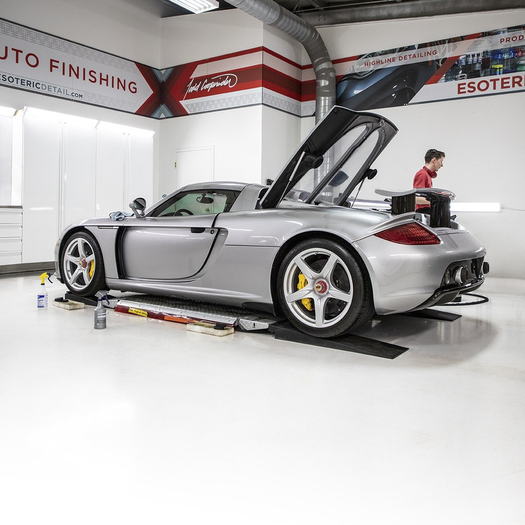 Silver Porsche Carrera GT showcased in an organized car detail shop featuring white VAULT® metal cabinets and parked on a clean white floor.